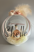 The Signature Luxe Bottle Bubble. This elegant gift turns  your bottles of choice into a stunning floating centerpieces. Ribbons of various colors gather at the top in a delicate bow, adding a graceful touch.