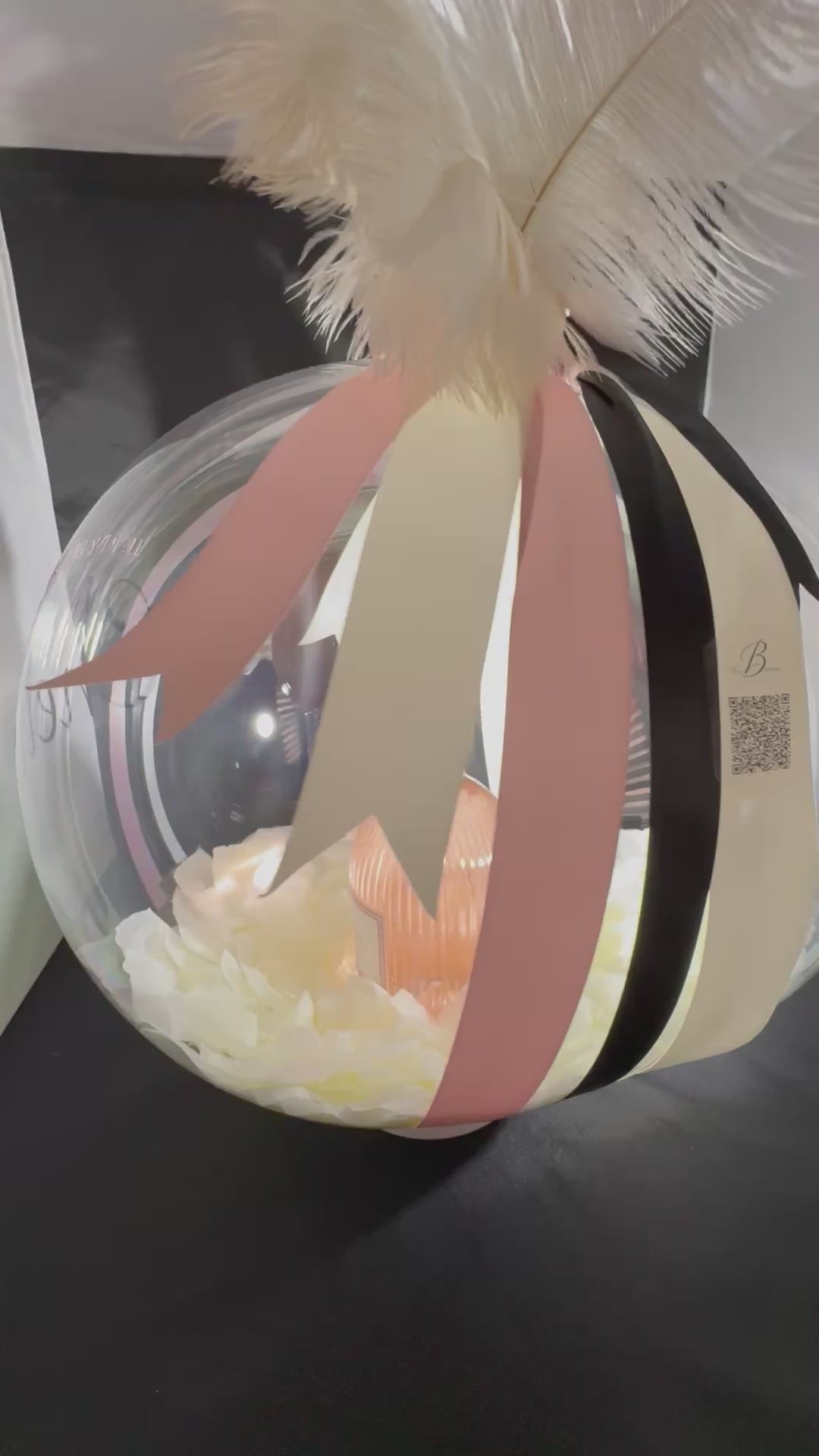 The Signature Luxe Bottle Bubble. This elegant gift turns  your bottles of choice into a stunning floating centerpieces. Ribbons of various colors gather at the top in a delicate bow, adding a graceful touch.